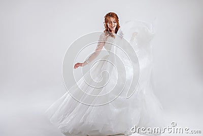 Delightful red-haired bride in a luxurious dress. Light background. Stock Photo