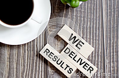 WE DELIVER RESULTS text on a wooden cubes on a wooden background Stock Photo