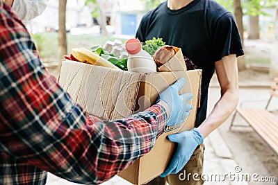 Delivering food to senior citizens in quarantine during Covid-19 Coronavirus epidemic. Courier in black shirt medical gloves Stock Photo