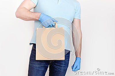 Delivery against Coronavirus 2019-nCov in pandemic Contactless delivery. Male hand in blue medical gloves holds craft paper bag on Stock Photo