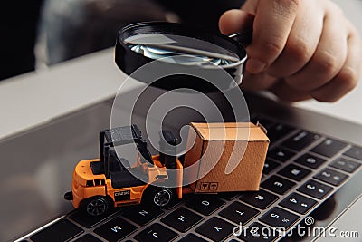 Delivery box, model of loader and a magnifying glass. Concept of internet commerce, online shopping, trade and turnover Stock Photo