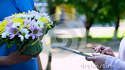 Delivery company client appending signature on tablet and receiving flowers Stock Photo