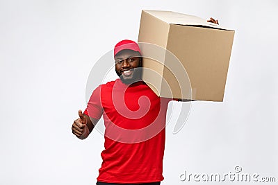 Delivery Concept - Handsome African American delivery man carrying package box. Isolated on Grey studio Background. Copy Stock Photo