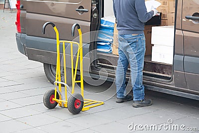 Delivery driver is unloading cargo van with goods to truck Stock Photo