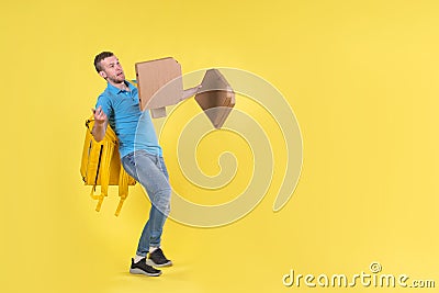 Delivery guy in blue uniform slipped and lost his balance and threw boxes of food from restaurant in direction. Clumsy Stock Photo