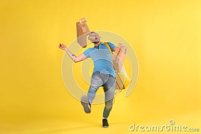 Delivery guy in blue uniform slipped and lost his balance and threw boxes of food from restaurant in direction. Clumsy Stock Photo