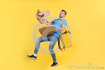 Delivery guy in blue uniform slipped and lost his balance and threw boxes of food from restaurant in direction. Clumsy Stock Photo