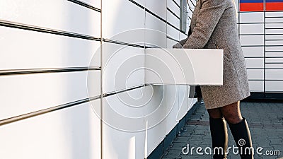 Delivery locker. Post automat terminal and hands with parcel courier box. Online purchase delivery service concept. Stock Photo