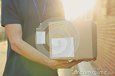 Delivery man with badge holds blank box outdoor Stock Photo