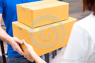 Delivery man in blue uniform handing parcel boxes to a woman Stock Photo