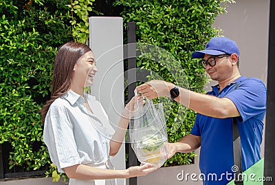 Delivery man delivering food to a beautiful Asian girl in front of the house Stock Photo