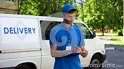 Delivery man filling parcel blank near company van, postal service, shipment Stock Photo