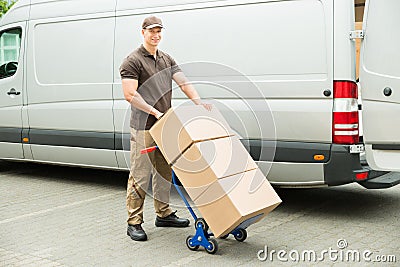 Delivery Man Holding Trolley With Cardboard Boxes Stock Photo