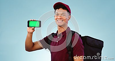 Delivery man, phone and green screen in studio with smile, mockup space and bag by blue background. Supply chain Stock Photo