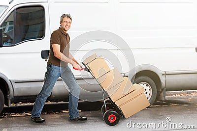 Delivery Man Pushing Parcels On Handtruck Stock Photo