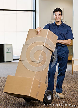 Delivery man in uniform pushing stack of boxes Stock Photo