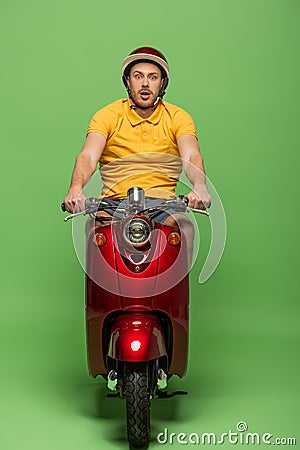 Delivery man in yellow uniform and helmet on scooter on green Stock Photo