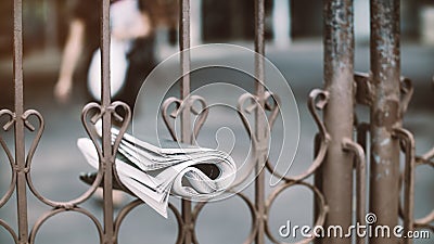 Delivery of a newspaper hang on the fence with the woman walking to keep it.16:9 style Stock Photo