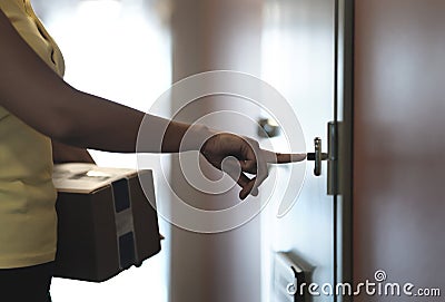 Delivery person ringing doorbell while delivering package to home door. Stock Photo