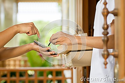 Delivery person signing for package on mobile phone Stock Photo