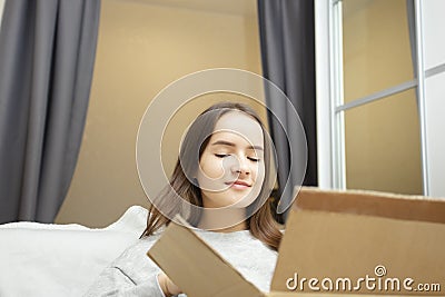 Delivery of postal items. A young woman opens a cardboard box parcel Stock Photo