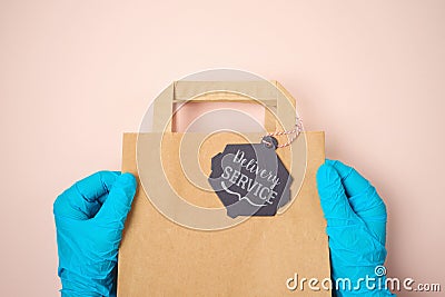 Delivery service concept with paper bag and hands with blue medical gloves. Cafe, restaurant and shop reopen after COVID -19 Stock Photo