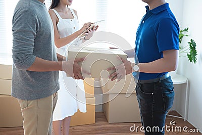 Delivery service worker in uniform delivering parcels to happy asian couple. Woman with tablet signing proof document.shopping Stock Photo