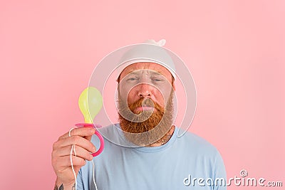 Delusion man with beard and tattoos acts like a little newborn baby with pacifier in hand Stock Photo