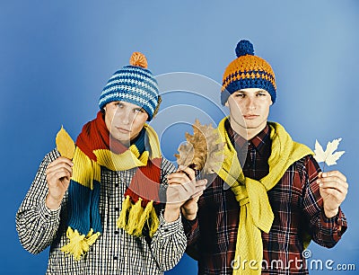 Demi season fashion concept. Men with serious faces on blue background. Twin brothers wearing warm hats and scarves Stock Photo