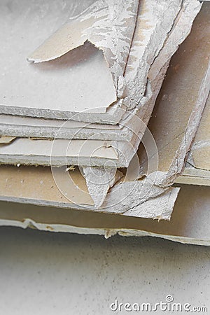 Demolished plasterboard wall, made of plaster and cardboard, with fragments of material and dust in a construction site Stock Photo