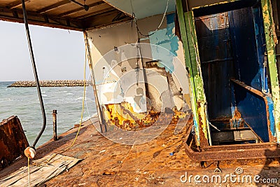 Demolished and rusty deck of a cargo ship with old bridge run aground on the Al Hamriyah beach in Umm Al Quwain, UAE Stock Photo