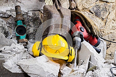 Demolition of walls. Electric hammer helmet and hearing protection lying on the rubble. Old brick and remodeled building wall. Stock Photo