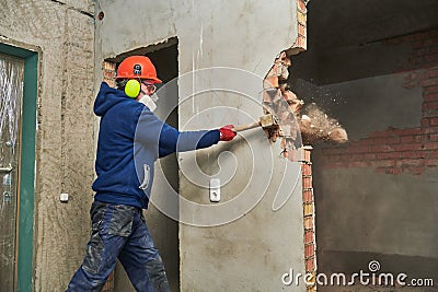 Demolition work and rearrangement. worker with sledgehammer destroying wall Stock Photo