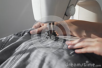 Denim or jeansecloth on sewing machine closeup. Seamstress hands at work process Stock Photo