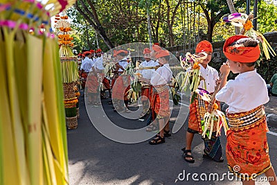 DENPASAR/BALI-JUNE 15 2019: Young Balinese boy wearing traditional Balinese headdress and traditional sarong bring sampian at the Editorial Stock Photo