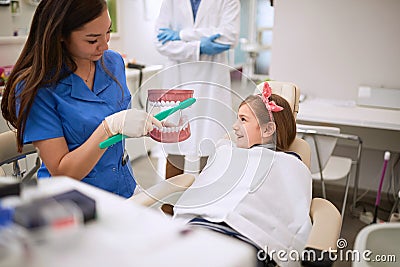 Dental assistant showing to child how to brushing her teeth Stock Photo