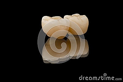 Dental bridge of 2 molar teeth. Close-up photo of metal free ceramic teeth crown isolated on black glass background Stock Photo