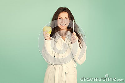 Dental care. Oral hygiene. Woman bathrobe hold toothbrush and apple. Personal hygiene. Girl cleaning teeth. Freshness Stock Photo