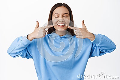 Dental clinic and people concept. Young woman smiling, pointing fingers at white perfect straight teeth, advertising Stock Photo