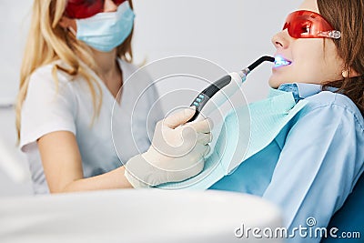 Dental curing light fixing composite resin fillers in boy teeth Stock Photo