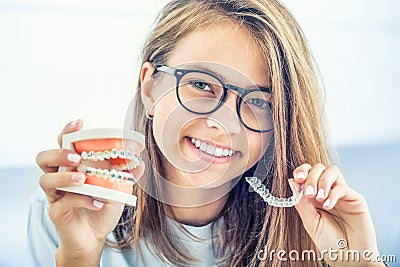 Dental invisible braces or silicone trainer in the hands of a young smiling girl. Orthodontic concept - Invisalign Stock Photo