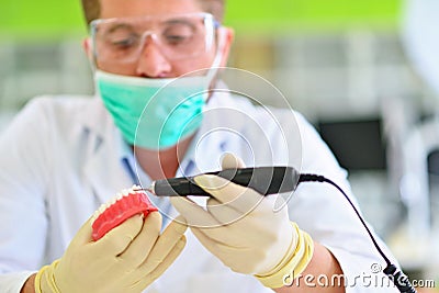 Dental prosthesis, dentures, prosthetics work. Prosthetics hands while working on the denture Stock Photo