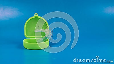 Dental retainer with green colored case, blue background Stock Photo
