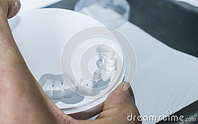 Dental technician is extracting teeth in the zirconia disc. Stock Photo