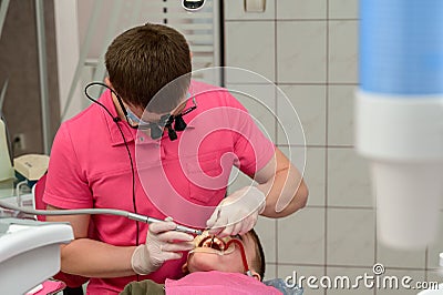 Dental treatment of a child, removal of caries with a drill, open mouth and ejector saliva. Stock Photo