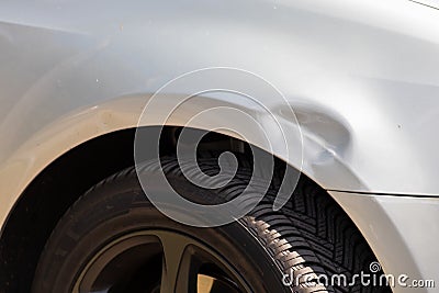 Dented car wing and fender with scratches and bumps after crash and car accident with hit-and-run driving and absconding shows nee Stock Photo