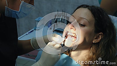 Dentist applies orthodontic glue on the teeth to the woman in the latch before installing the bracket system. Visit to Stock Photo