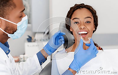 Dentist applying invisible aligner on female patient teeth Stock Photo