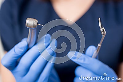 Dentist with blue gloves holding dental equipment - drill and mirror at the dental office Stock Photo