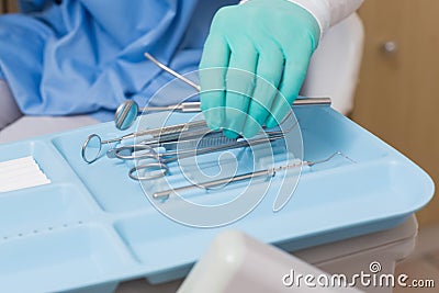 Dentist in blue scrubs picking up tools Stock Photo